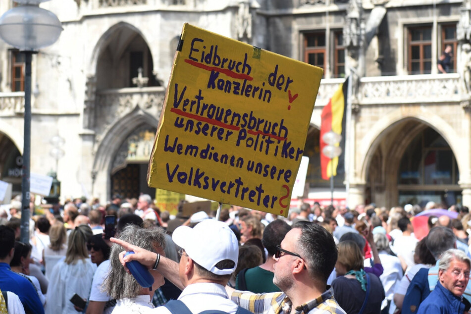 "Eidbruch der Kanzlerin" steht auf einem Schild, das einer der Demo-Teilnehmer hochhält.