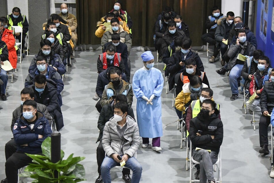 Peking: Eine Medizinerin geht zwischen Menschen mit Mund-Nasen-Bedeckung entlang, die gerade eine Impfdosis mit einem Corona-Impfstoff erhalten haben und nun 30 Minuten warten müssen, um zu sehen, ob sie Reaktionen zeigen.