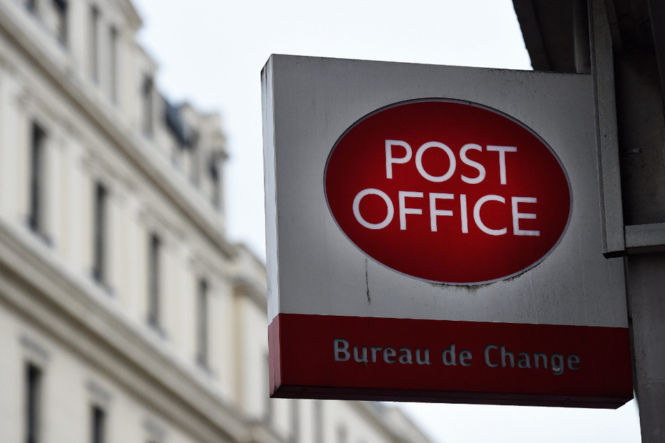 Ein Post Office-Schild hängt vor einem Postamt in London.