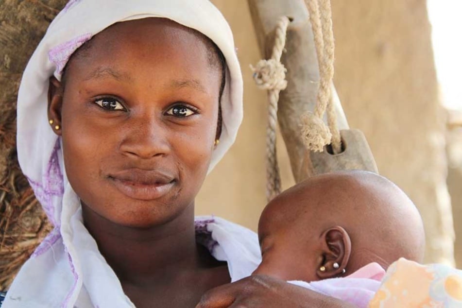 Die 13-jährige Minata hält im Hof ihres Elternhauses in der Region Koulikoro im Zentrum Malis ihre etwa zweieinhalb Monate alte Tochter Dioulaba im Arm.