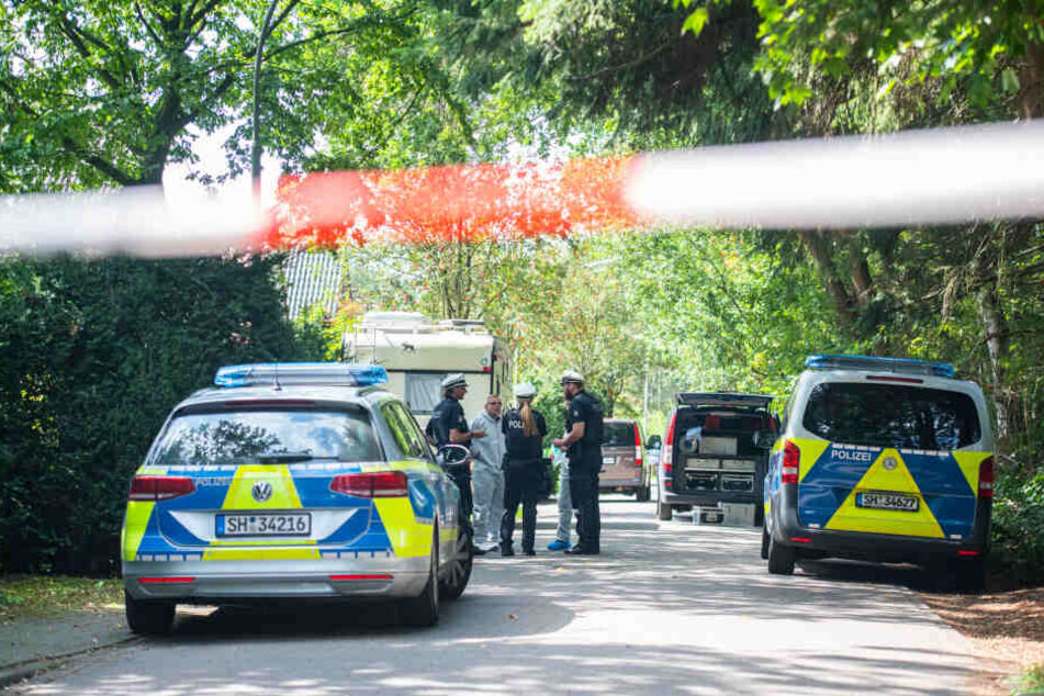 Polizisten stehen vor einem Wohnhaus, in dem die Leiche der Frau gefunden wurde.
