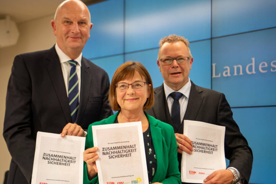 Dietmar Woidke (l.),Ursula Nonnemacher, und Michael Stübgen halten nach einer Pressekonferenz zur Vorstellung des neuen Koalitionsvertrags die ausgedruckten Exemplare des Vertrags in den Händen. (Archivbild)