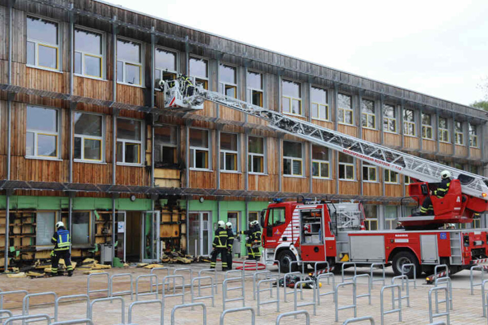 Das Ausmaß des Feuers ist am Gebäude der Schule deutlich zu sehen. Die Einsatzkräfte mussten die Holzverkleidung lösen.