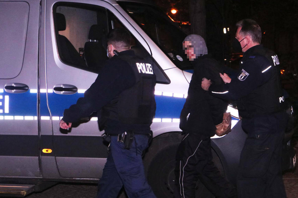 Polizisten führen einen 20-Jährigen ab, der im Verdacht steht, einen jungen Mann niedergestochen zu haben.
