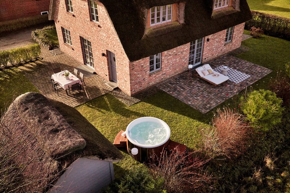 Drei Terrassen und ein gepflegter Garten mit Rasenfläche schaffen vielfältige Rückzugsorte im Freien.