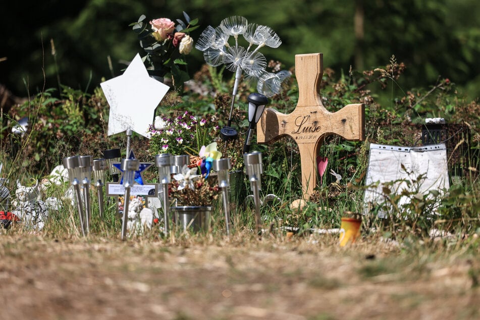 Ein Holzkreuz, Blumen und Lichter stehen am Waldrand an der Stelle, an der das Mädchen Luise (†12( tot gefunden wurde. (Archivfoto)