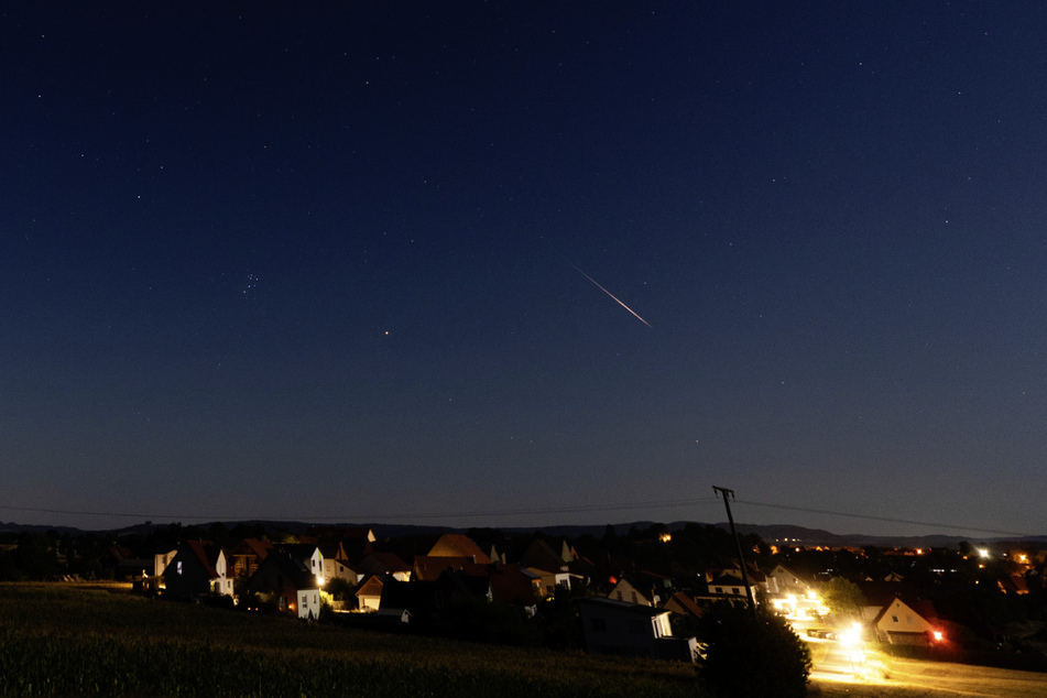 Eine Sternschnuppe verglüht im August am Nachthimmel über Bayern.
