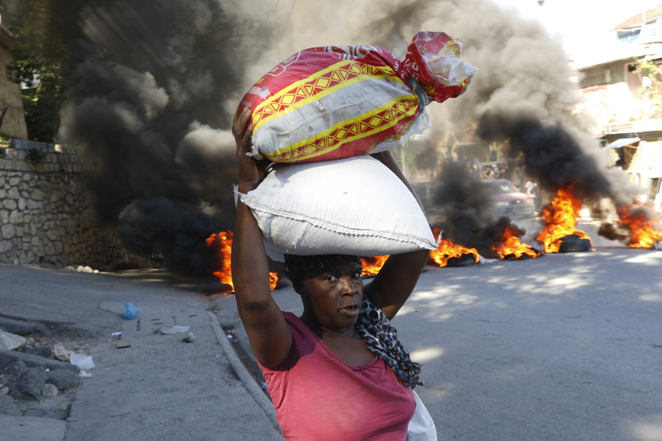 Eine Frau geht an einer brennenden Straßenblockade vorbei.