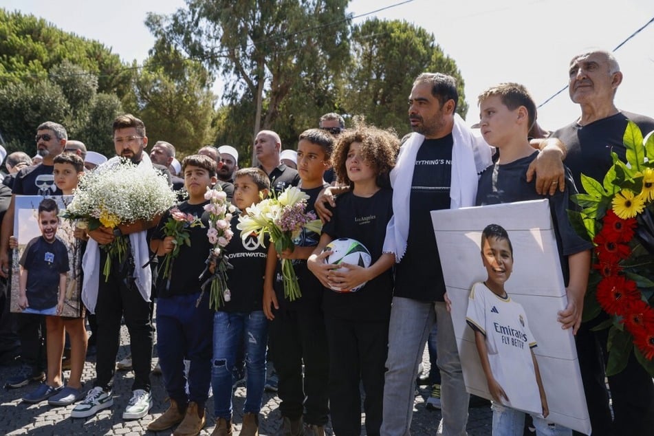 Mourners comfort each other during the funeral of 11-year-old Guevara Ibrahim, who was killed in a strike on the Druze town of Majdal Shams.