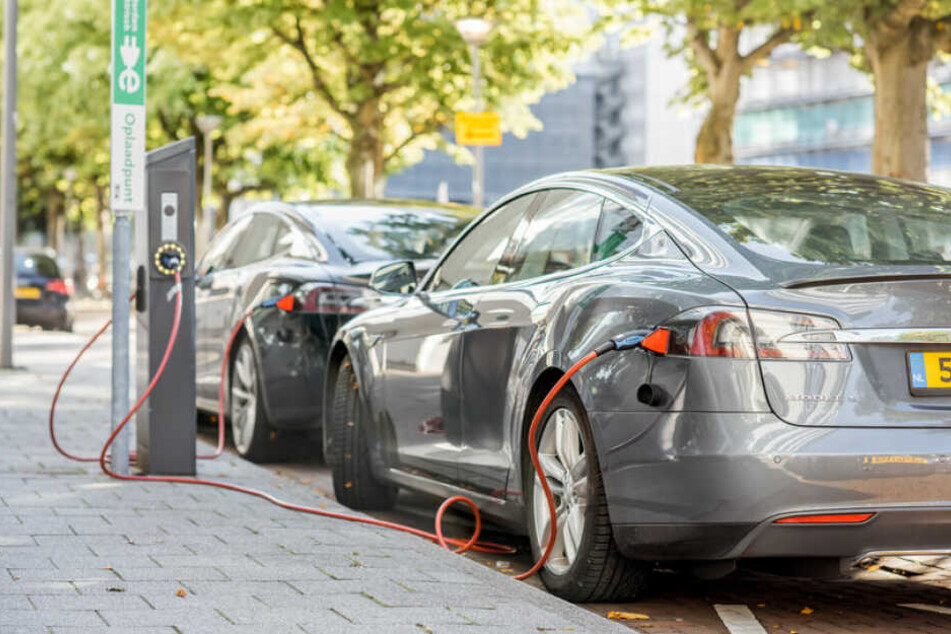 Tesla-Autos hängen an Ladesäulen. (Symbolbild)