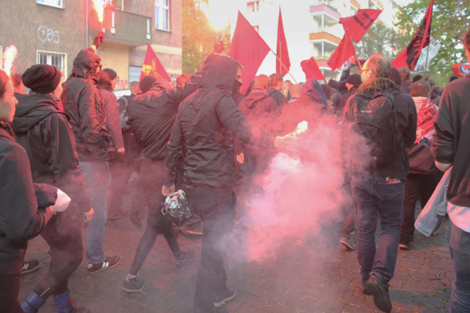 Vermummte Teilnehmer einer Demonstration halten am 30.04.2016 in Wedding brennende Bengalos und Fahnen hoch.
