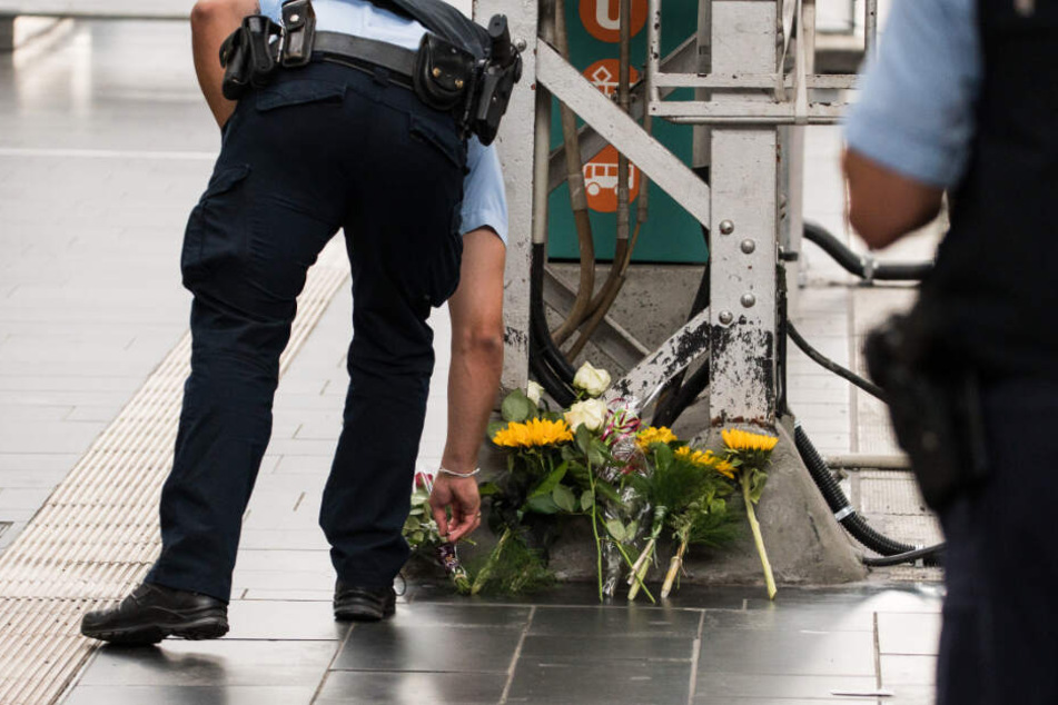 Ein Polizist legt am Unglücksort Blumen ab.