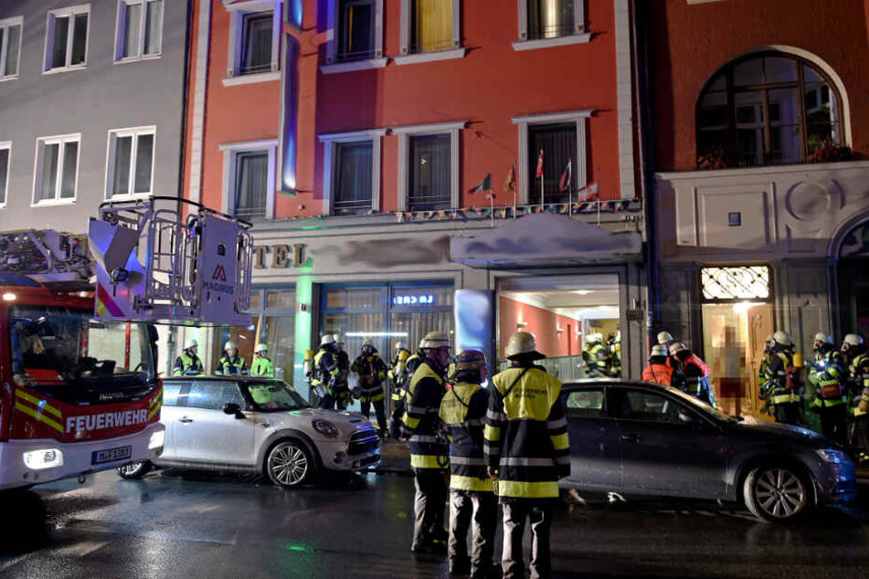 Feuerwehrleute stehen vor dem Hotel, in dessen Keller ein Brand ausgebrochen war.