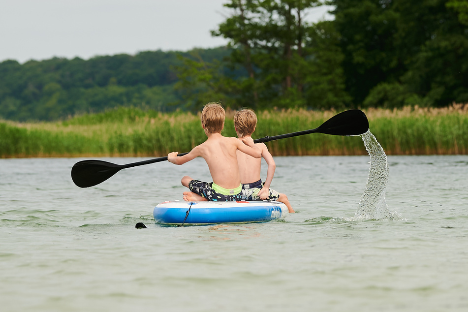 Zwei Kinder paddeln auf einem See in Eberswalde.
