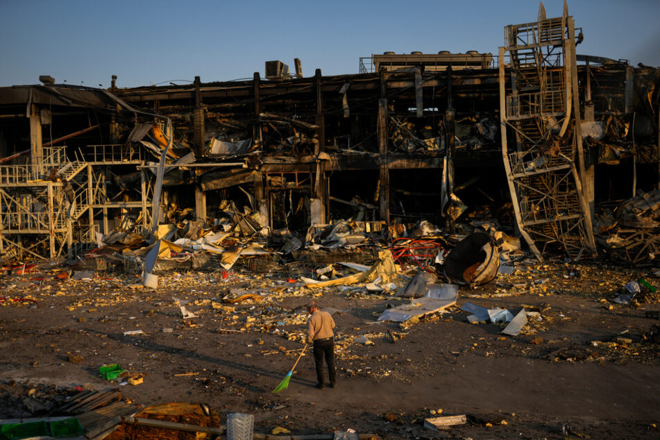 Ein Mann fegt die Trümmer neben einem Einkaufs- und Unterhaltungszentrum in Odessa zusammen.