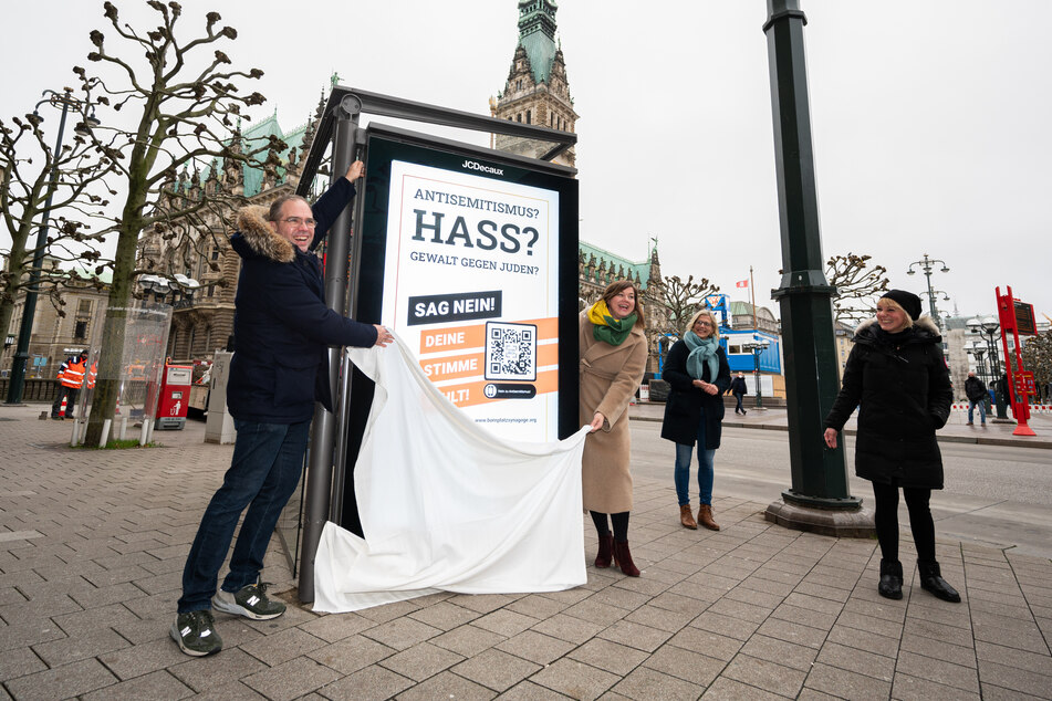 Unterstützer der Initiative enthüllen ein Plakat in der Innenstadt.