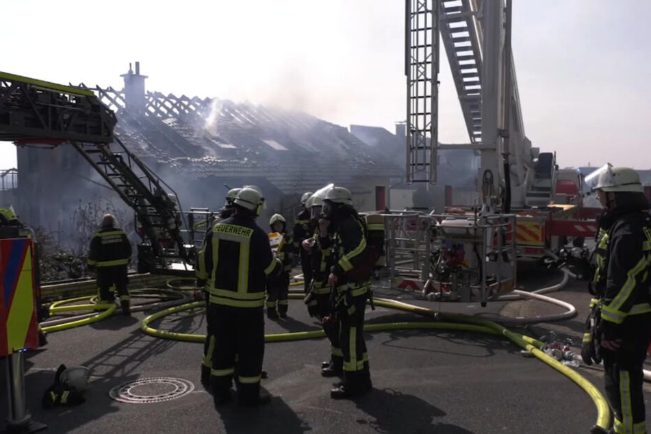 Feuerwehrleute stehen vor den völlig zerstörten Häusern.