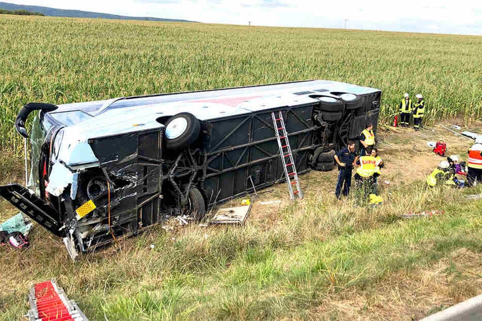 Der umgekippte Bus liegt auf der Seite. Rettungskräfte sind vor Ort.