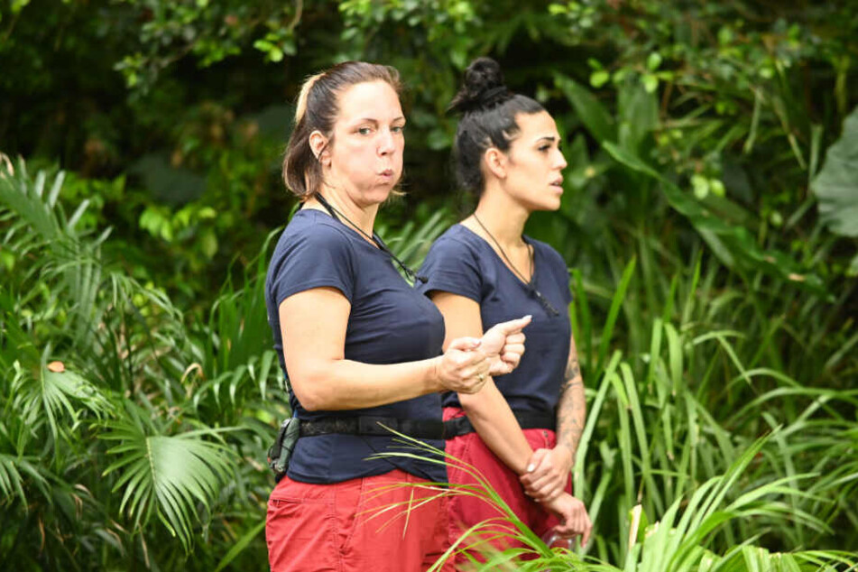 Dschungelprüfung"Heißer Stuhl": Die Witwe von Malle-Jens fährt eine Runde Gesichtskirmes, Elena (r.) sucht in der Ferne den nächsten Stein des Anstoßes.