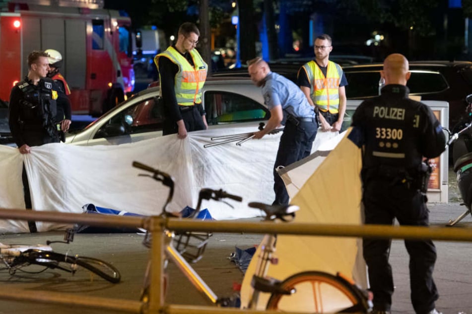 Polizisten errichten einen Sichtschutz für die verunglückte Frau.