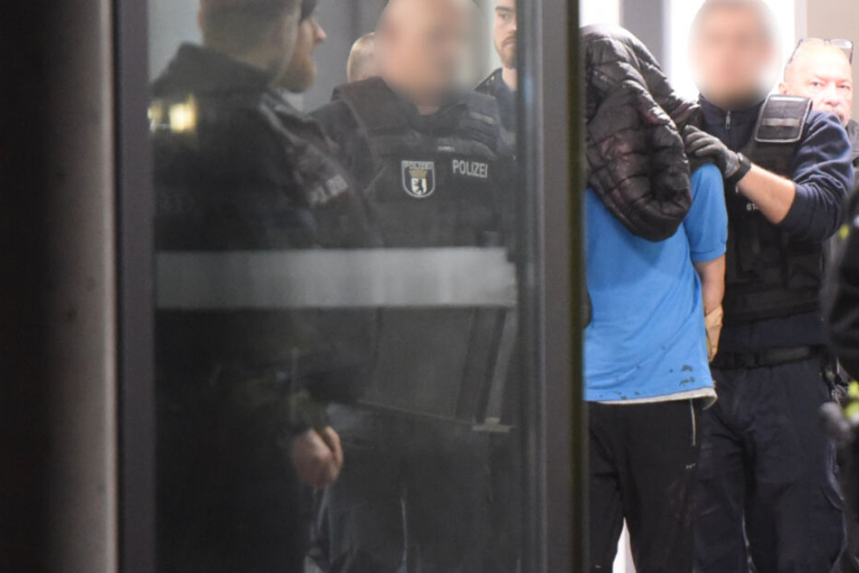 Polizisten führen den Verdächtigen ab.