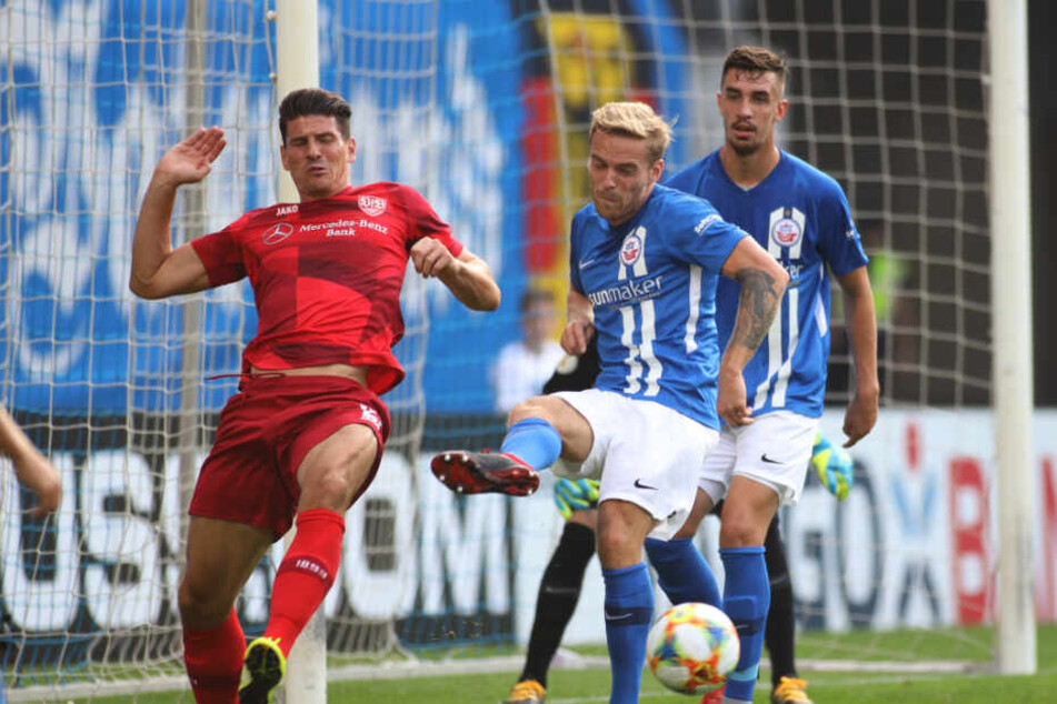 Rostocks Nils Butzen (M) kämpft mit Stuttgarts Mario Gomez (l) um den Ball.