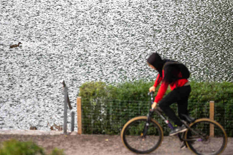 Ein Fahrradfahrer vor einer spätsommerlichen Regenwand in Thüringen.