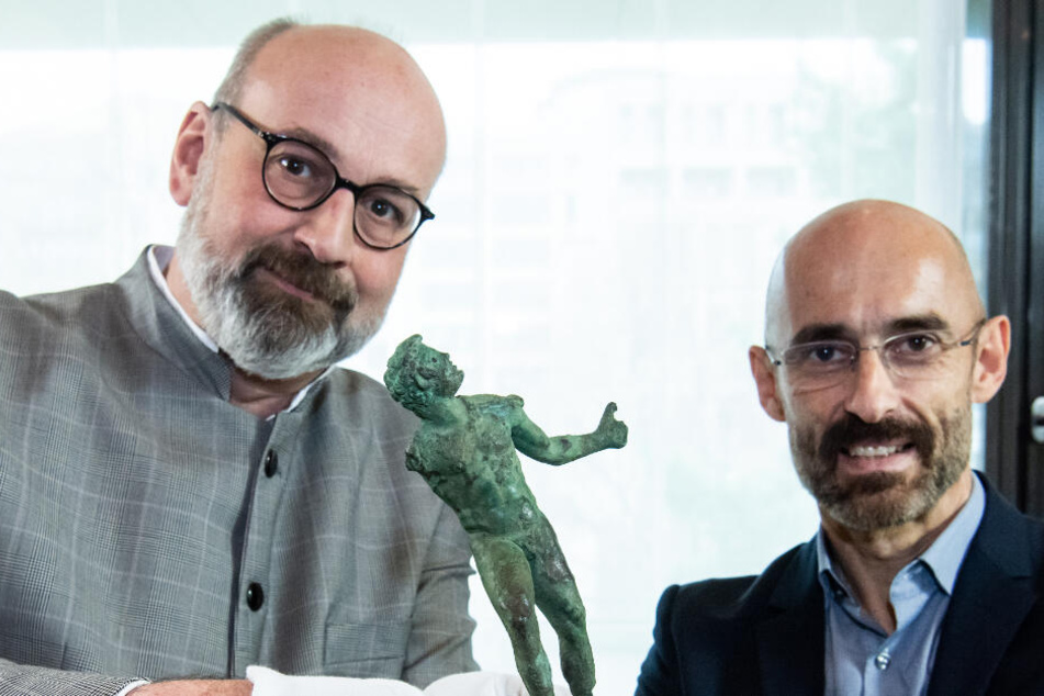 Martin Maischberger (r), stellvertretender Direktor der Antikensammlung der Staatlichen Museen zu Berlin, übergibt Martin Eberle, Direktor der Museumslandschaft Hessen Kassel, die Bronzestatuette.