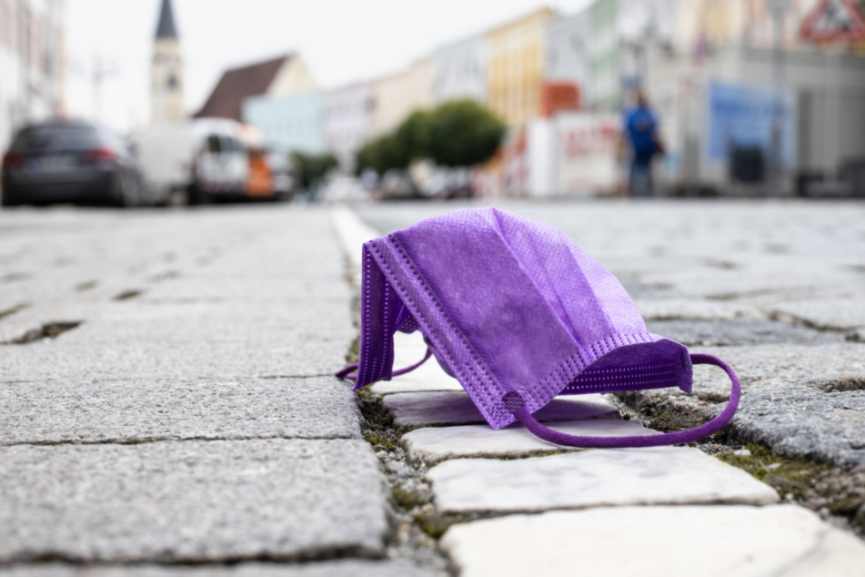 Eine violette medizinische Maske liegt in der Altstadt von Mühldorf am Inn. Mühldorf am Inn zählt aktuell zu den am stärksten von Corona betroffenen bayerischen Regionen.