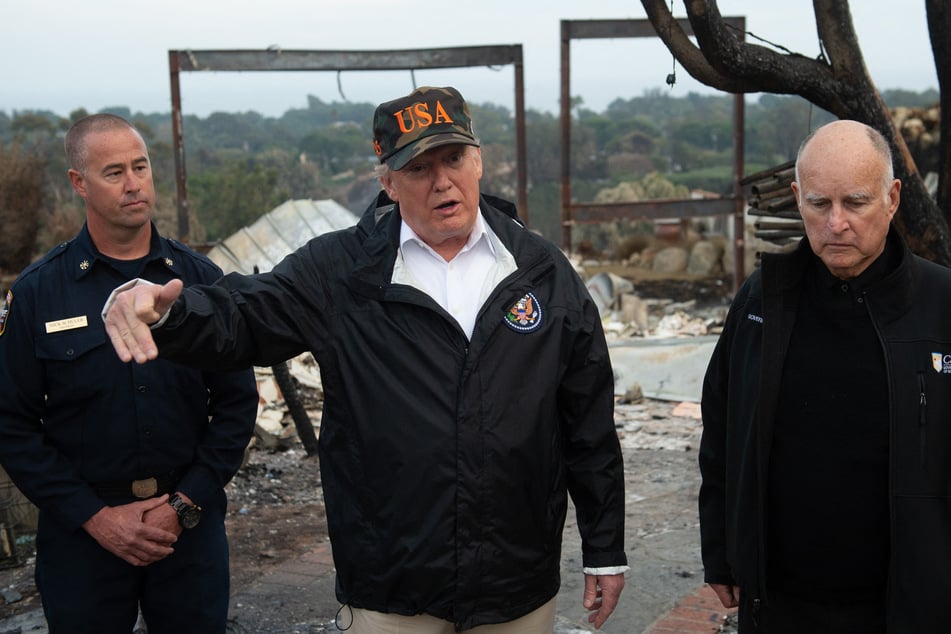 Then-President Donald Trump (c.) and California Governor Jerry Brown (r.) view damage from the wildfires in Malibu, California, on November 17, 2018.