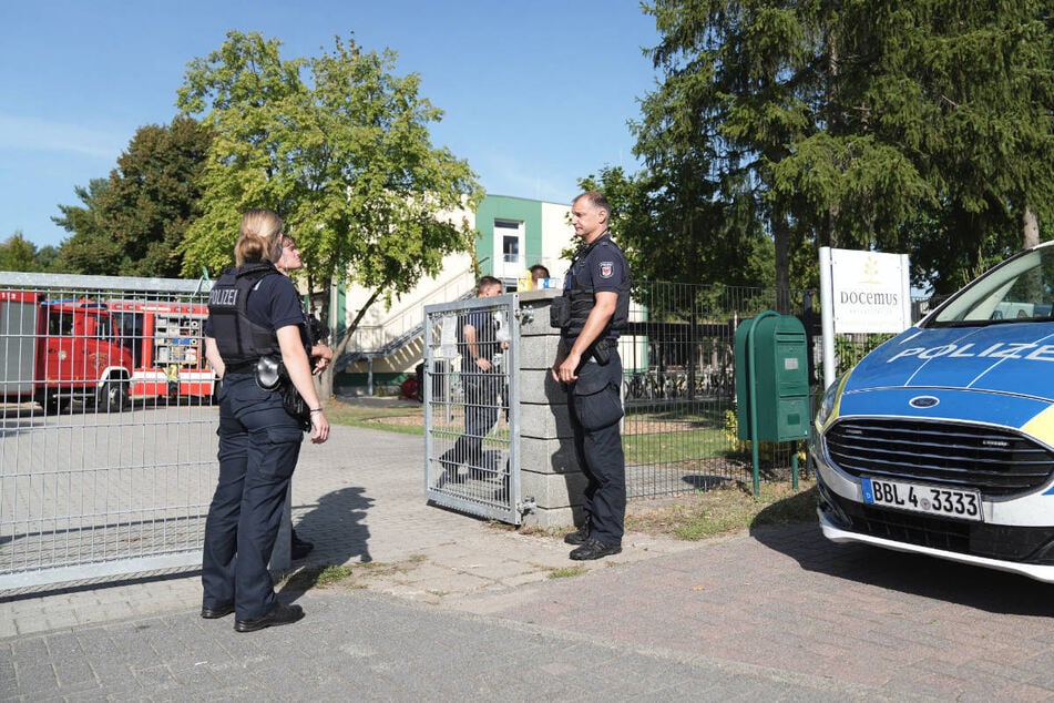 Polizeibeamte stehen vor dem Gelände der Docemus-Privatschule, wo sich die Tat am frühen Nachmittag ereignet hat.