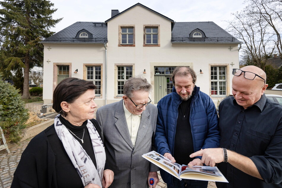 Heike Fiedler (v.l.), Fritz Ehrentraut (88, der letzte Meister der Schmiede), Thomas Morgenstern (70) und Udo Schriefers (59) betrachten alte Fotos vorm sanierten Denkmal.