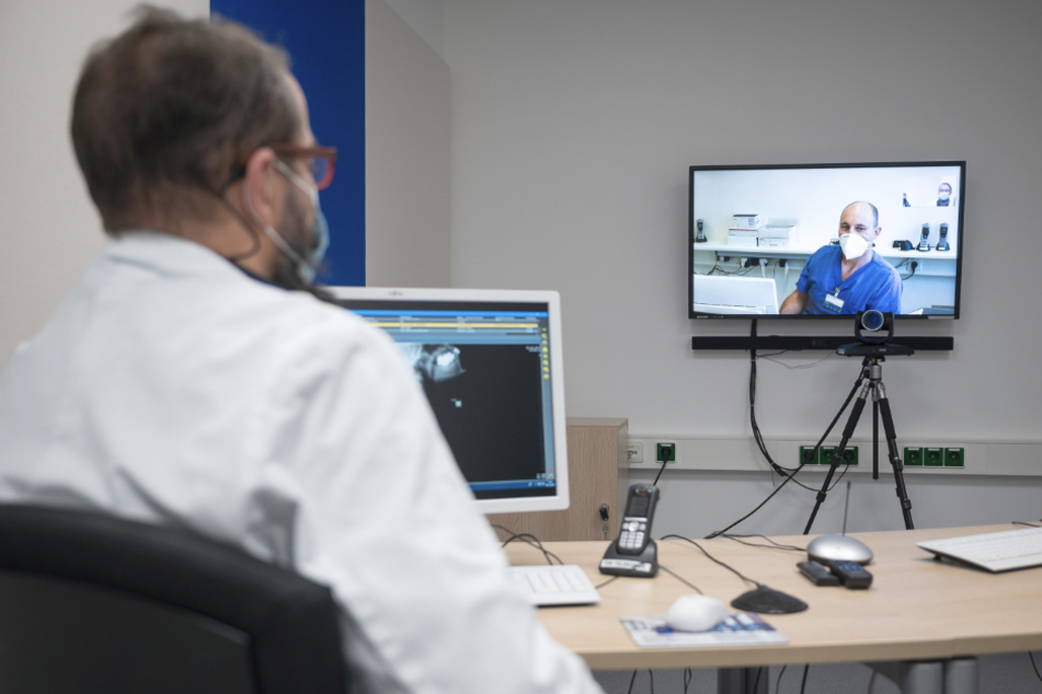 Ralph Brunner (r.), Oberarzt in der Klinik für Anästhesiologie, Intensivmedizin, Notfallmedizin und Schmerztherapie im RKH Krankenhaus Mühlacker, spricht bei einem Pressegespräch im Zentrum für Telemedizin des RKH Klinikum Ludwigsburg über eine Videoschaltung aus Mühlacker mit einem Techniker (l.).