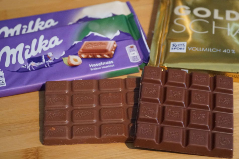Schokoladentafeln der Marken Ritter Sport und Milka liegen auf einem Tisch.