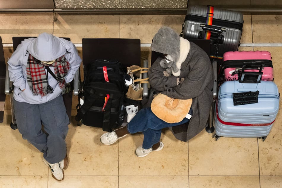 Zwei Reisende sitzen mit ihrem Gepäck im Terminal fest.