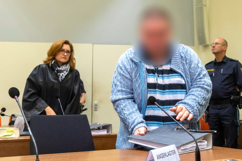 Der Angeklagte steht zum Prozessauftakt an seinem Platz im Gericht. Links steht seine Anwältin Birgit Schwerdt.