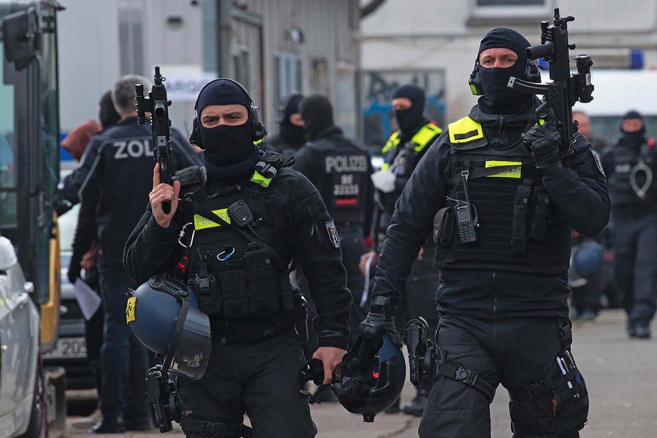 Einsatzkräfte der Polizei gehen mit ihren Waffen in der Hand über ein Gelände in Berlin-Lichtenberg. Mit einer Razzia gehen die Beamten gegen mutmaßliche, international operierende Drogenhändler vor.