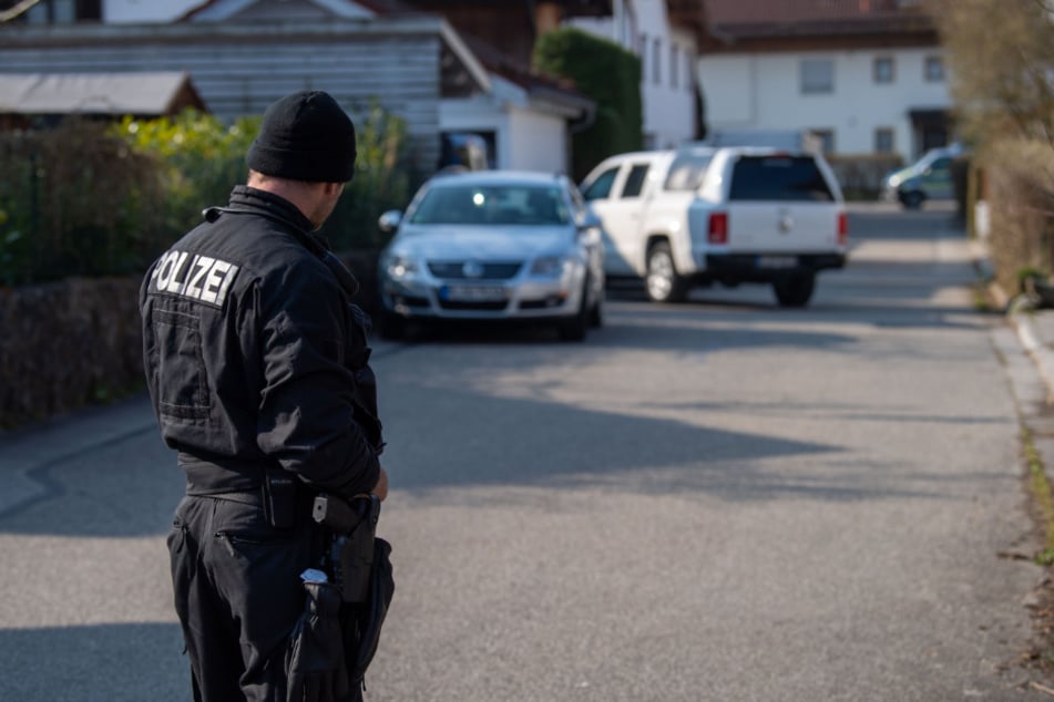 Ein Polizist steht auf einer Straße vor einem Haus in Vogtareuth, in dem drei Tote Menschen aufgefunden worden waren.