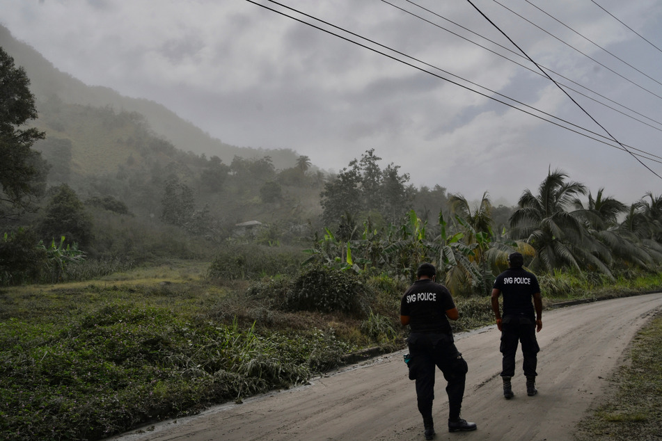 Kingstown: Polizisten patrouillieren nach dem Ausbruch des Vulkans La Soufriere auf einer aschebedeckten Straße, um Menschen davon abzuhalten, sich dem aktiven Vulkan zu nähern.