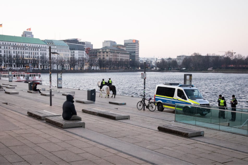 Hamburg: Nur wenige Menschen sind am Abend am Jungfernstieg unterwegs, während Polizeibeamte die Maßnahmen gegen die Ausbreitung des Coronavirus kontrollieren. 