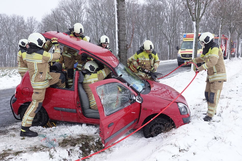 Feuerwehrleute hebeln das Dach des Unfall-Autos auf.