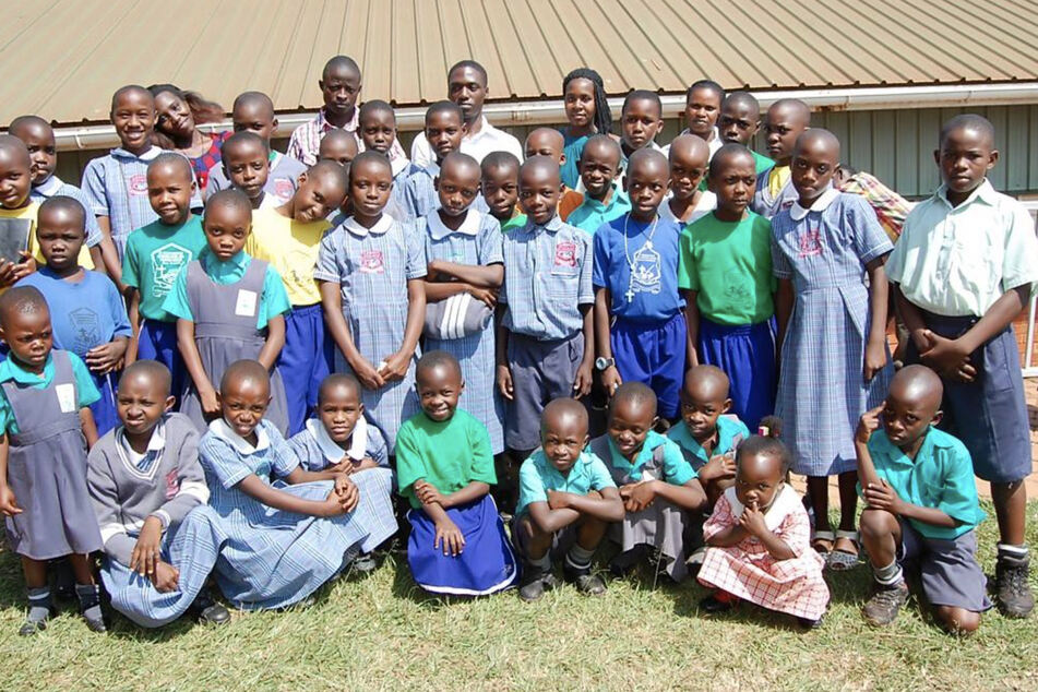 Students at St. Balikuddembe Primary School pose for a photo on a sunny day.