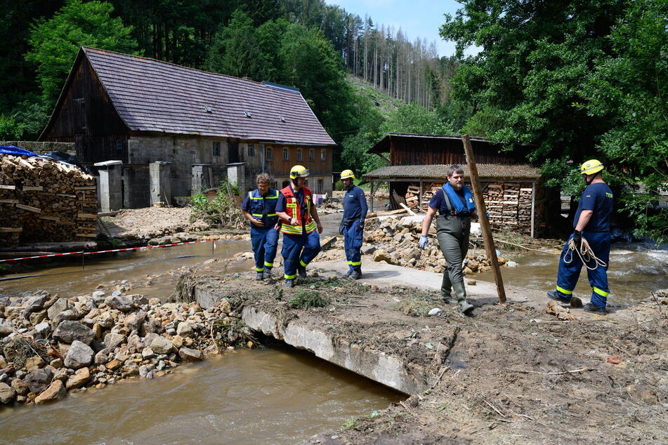 Einsatzkräfte des THW beseitigen am Krippenbach Geröll und begutachten die Schäden.