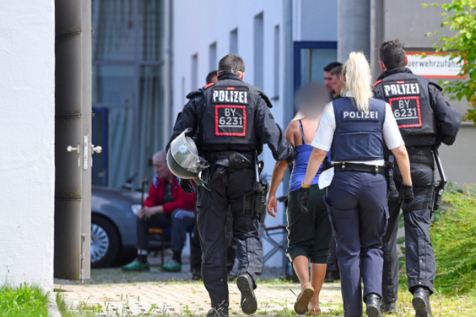 Einsatzkräfte der Polizei führen vor der Polizeiinspektion in Miesbach eine Tatverdächtige ab.