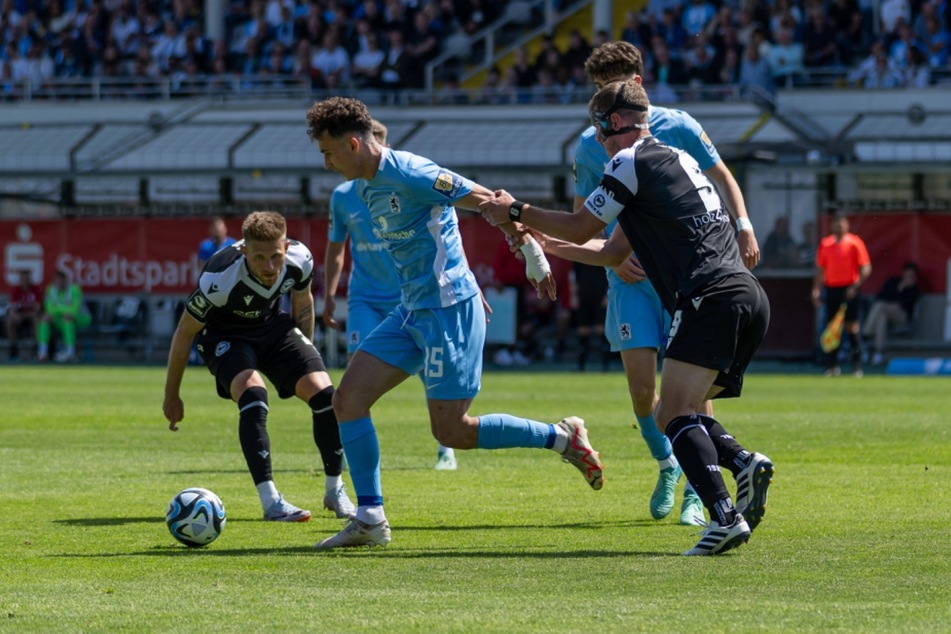 Bielefelds Kapitän Fabian Klos (r.) hielt Münchens Michael Glück (M.) am Arm fest und sah dafür Gelb.