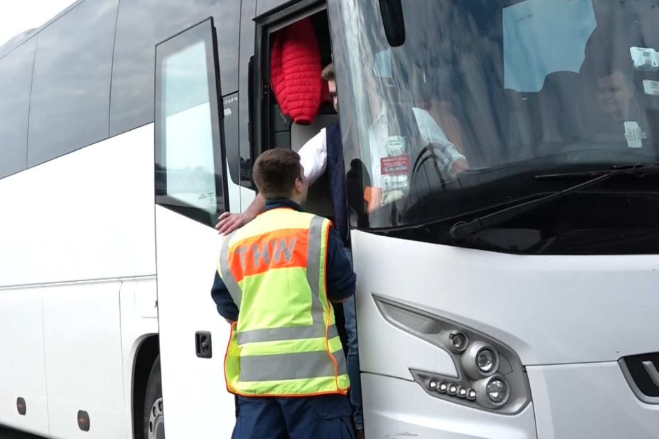 Ein Mitarbeiter des Technischen Hilfswerks an einem Reisebus.