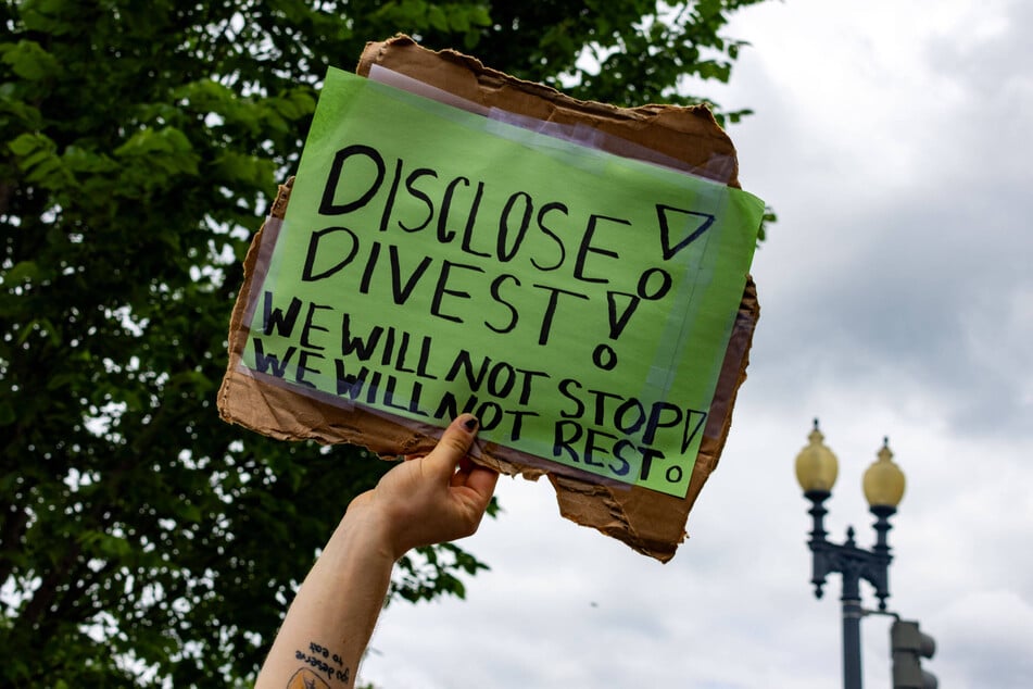 A student raises a sign calling on George Washington University to divest from Israel during a pro-Palestine demonstration.