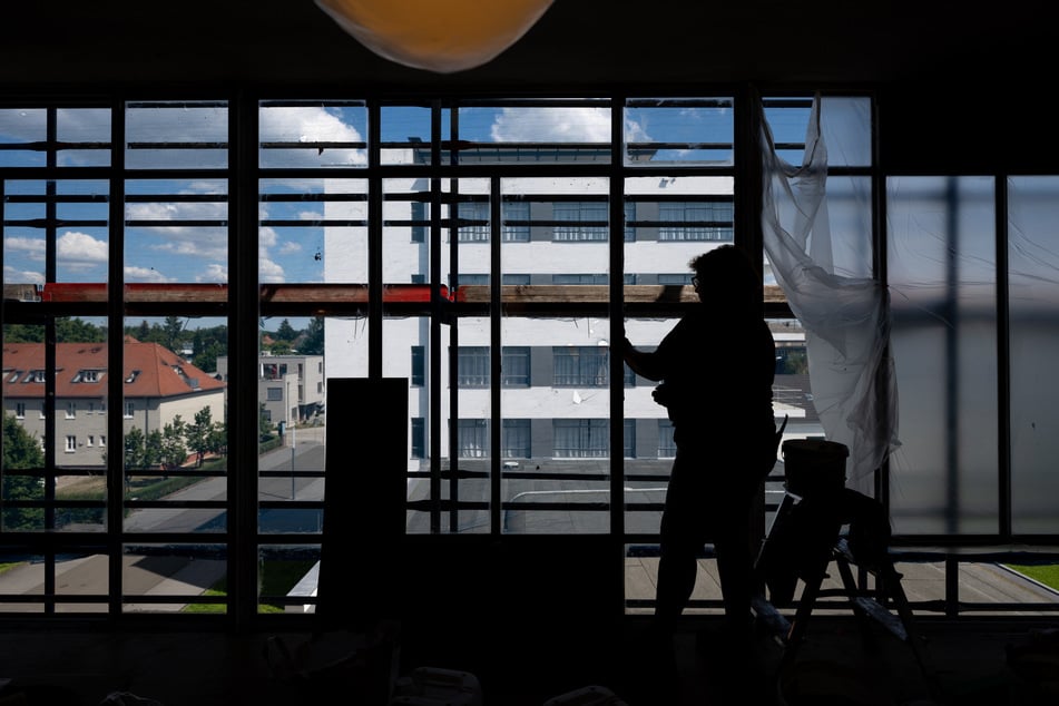 Glasermeisterin Sabine Elß passt im Bauhaus Gebäude restaurierte Fensterscheiben in Rahmen aus Metall ein. Bis Frühjahr 2023 sollen die Arbeiten noch andauern.