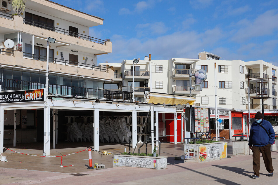 Ein Mann geht an einer geschlossenen Bar in Magaluf vorbei. Bald darf dieses Lokal wieder öffnen.