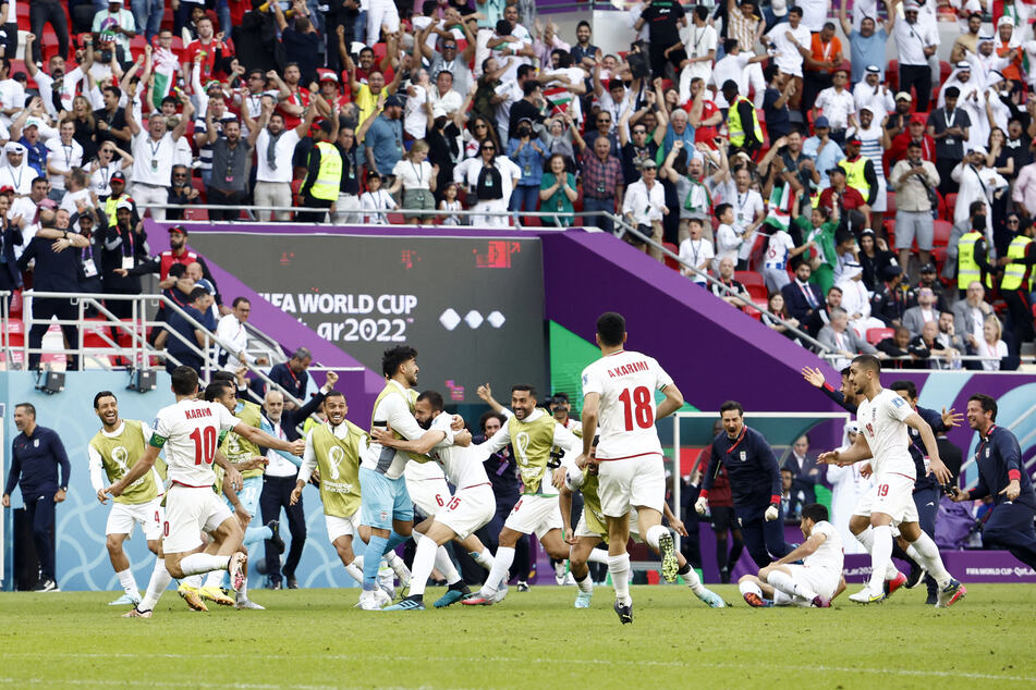 Iran's entire bench spills onto to the field in ecstasy after Roozbeh Cheshmi puts Iran into the lead in the 98th minute.